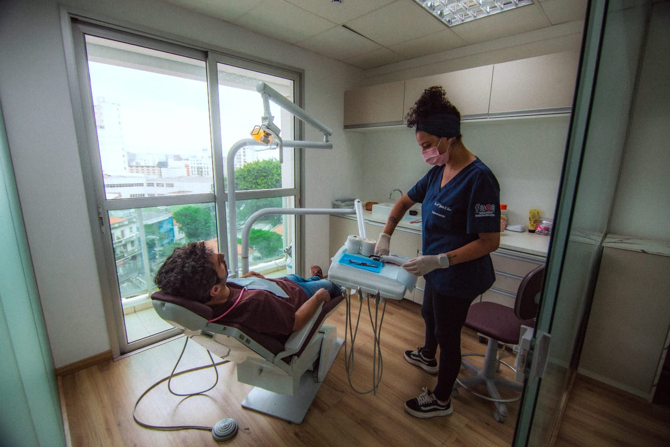 Dra. Maria Gabriela em atendimento no consultório, com luz natural e vista para a cidade